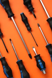 Photo of Set of screwdrivers on orange background, flat lay