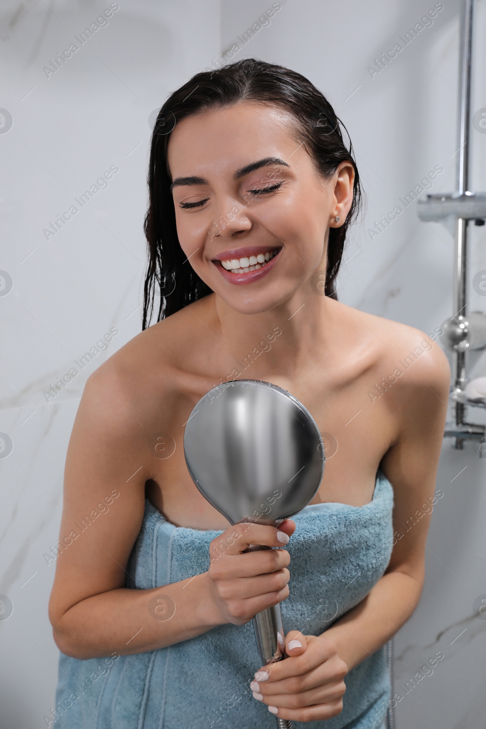 Photo of Beautiful young woman with towel singing while taking shower