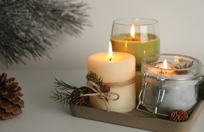 Photo of Composition with burning scented conifer candles and Christmas decor on light table