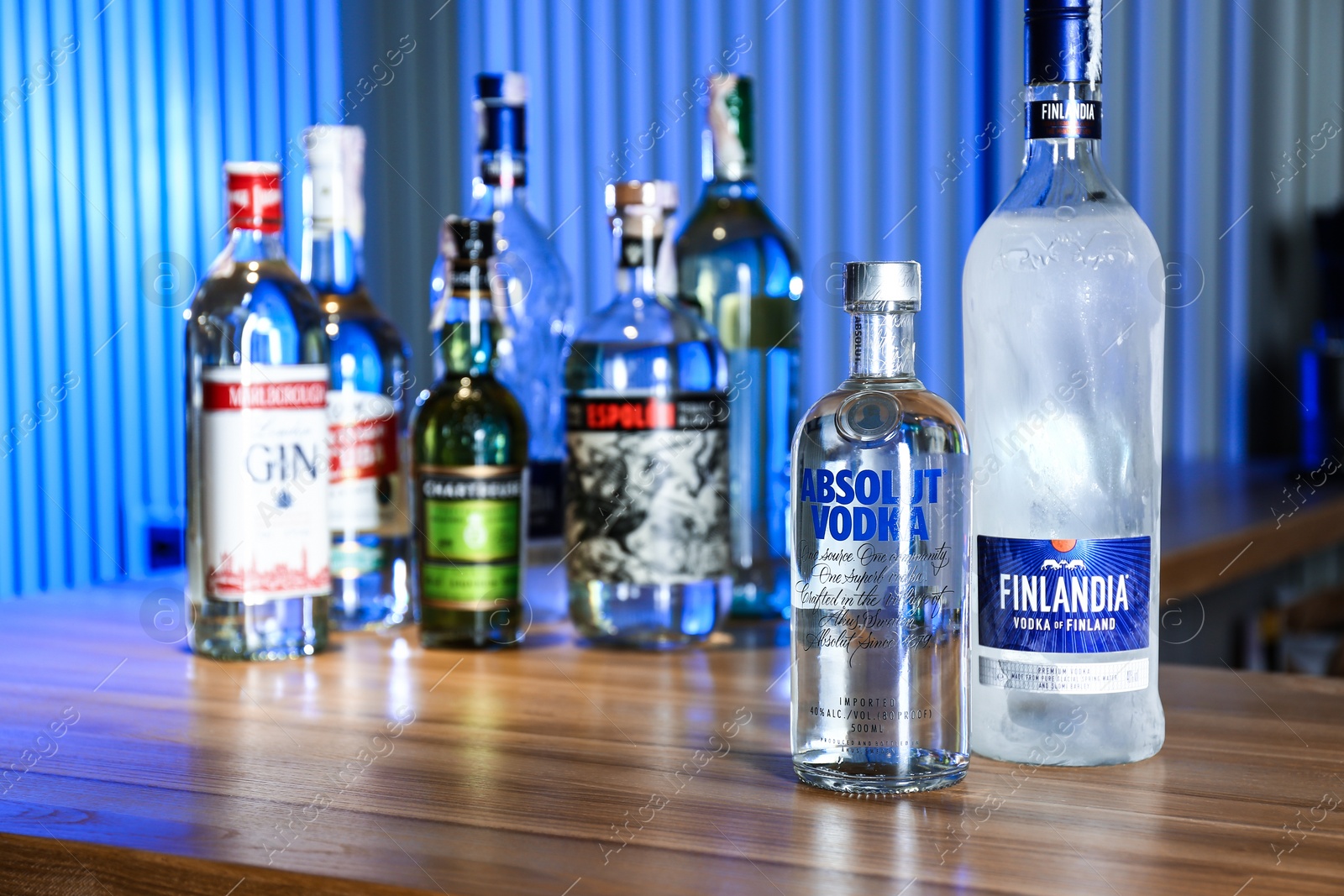 Photo of MYKOLAIV, UKRAINE - SEPTEMBER 24, 2019: Bottles of global vodka brands on wooden counter in bar. Space for text