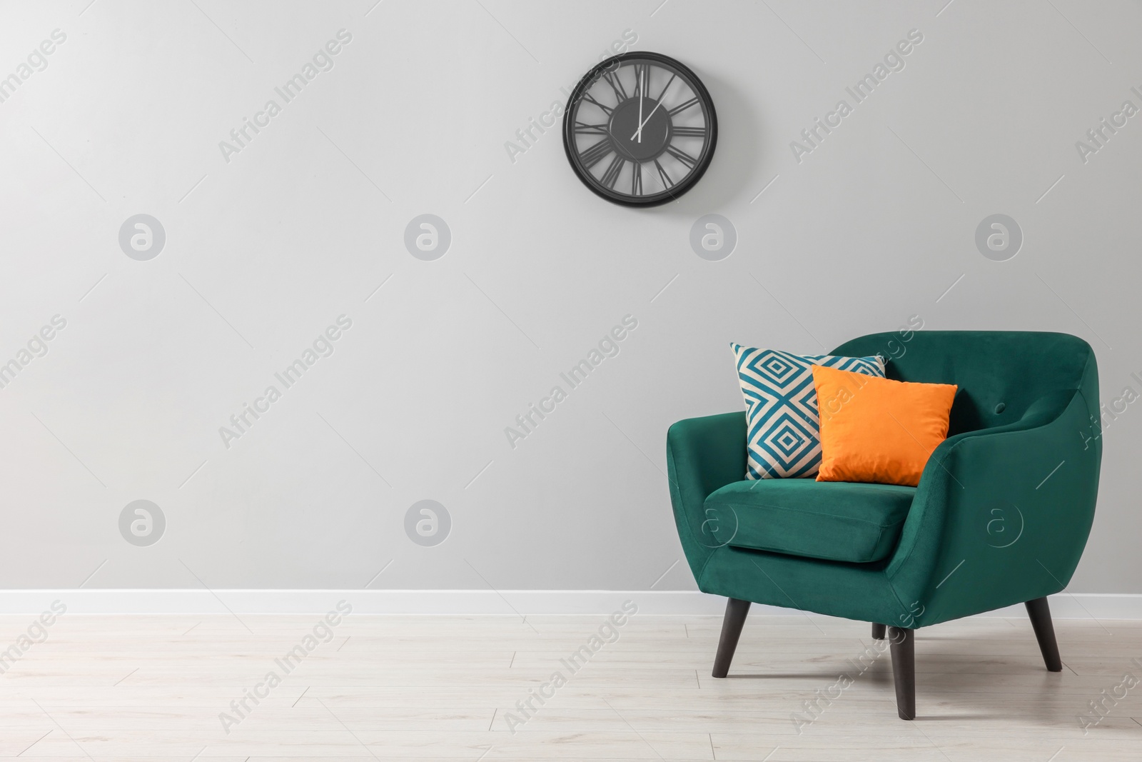 Photo of Comfortable armchair with cushions near light grey wall indoors. Space for text