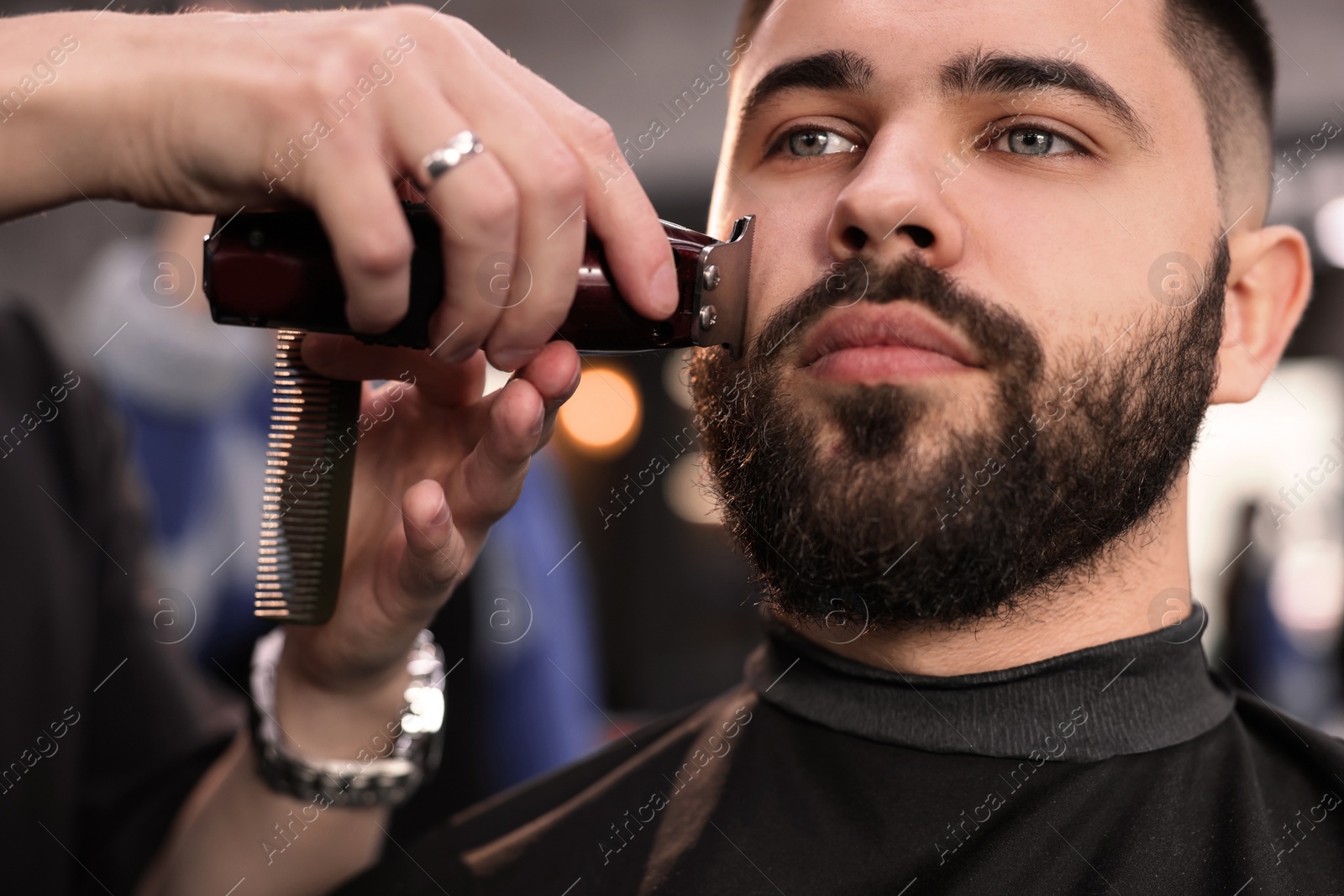 Photo of Professional hairdresser working with client in barbershop, closeup