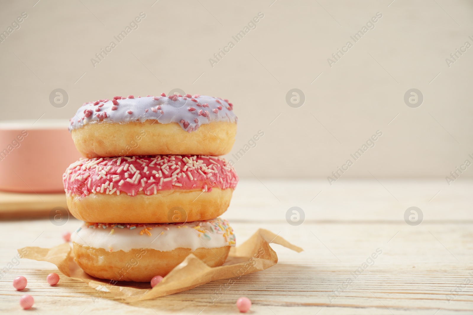 Photo of Delicious glazed donuts on white wooden table. Space for text