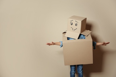 Photo of Cute little child in cardboard costume on color background. Space for text