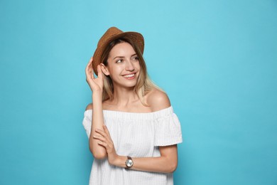 Photo of Beautiful young woman wearing straw hat on light blue background, space for text. Stylish headdress