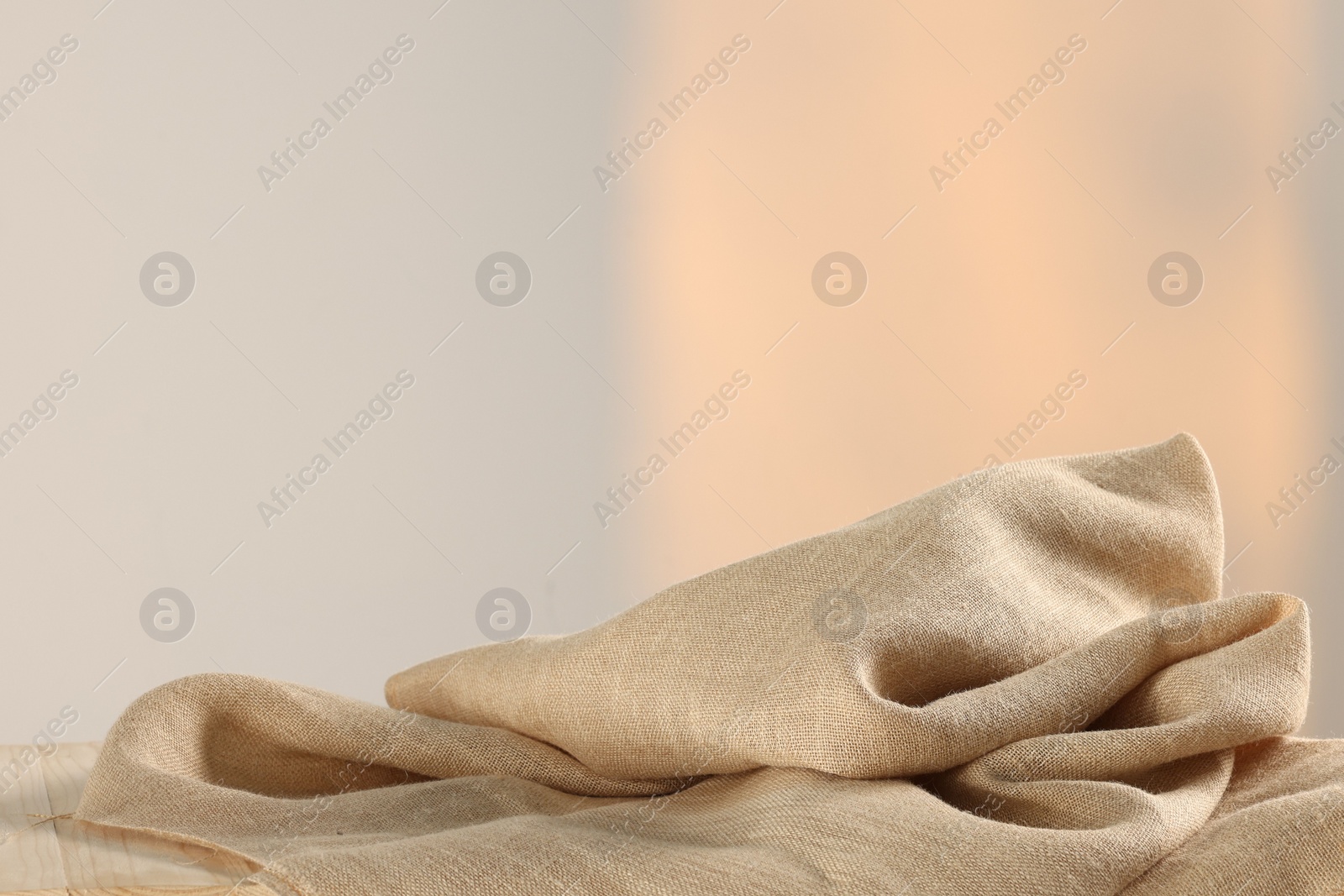 Photo of Natural burlap fabric on wooden table against light background. Space for text