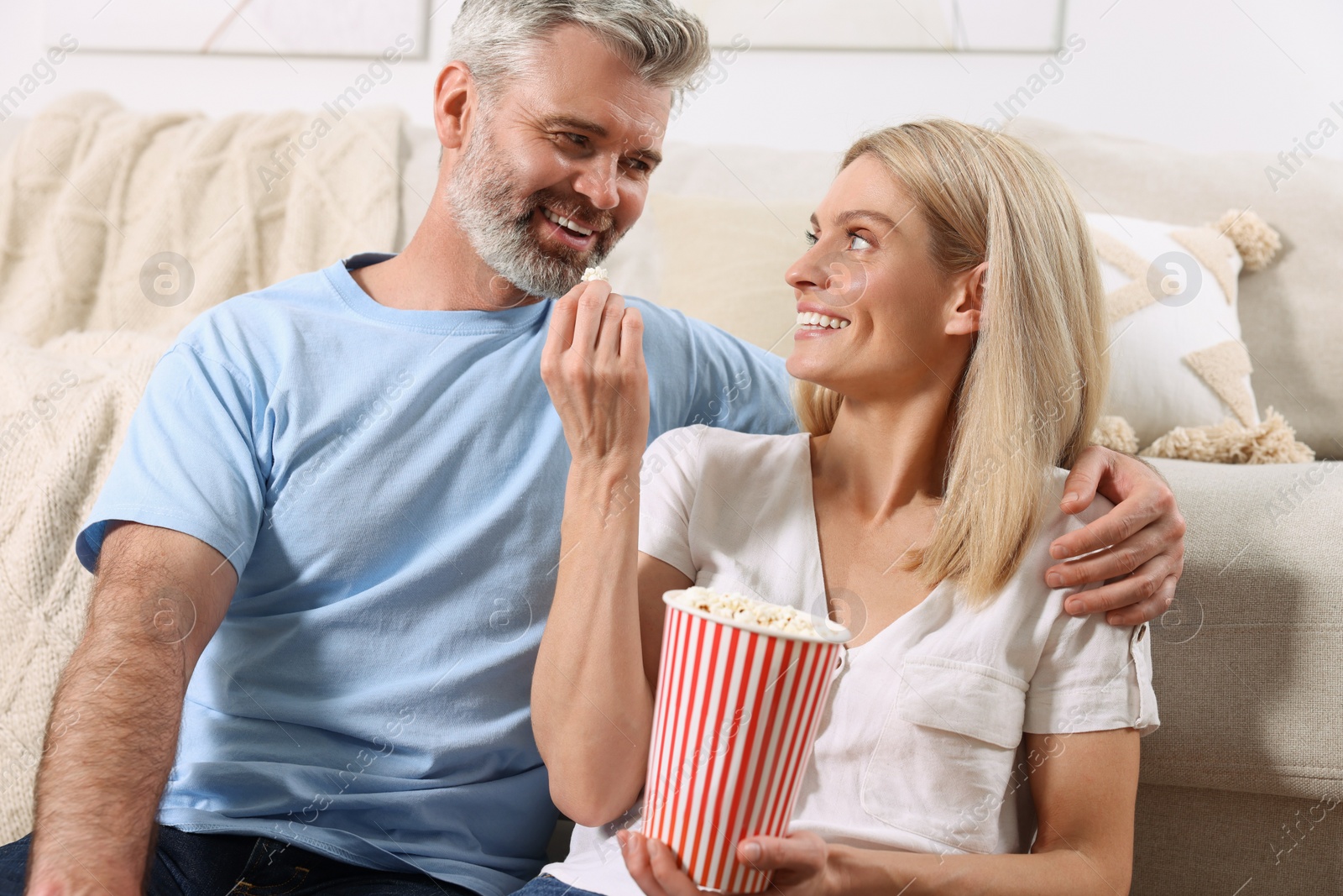 Photo of Happy affectionate couple with popcorn spending time together at home. Romantic date