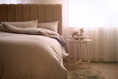 Photo of Comfortable bed with soft blanket near window indoors, closeup