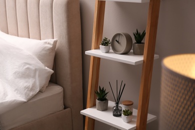 Stylish bedroom interior with decorative ladder and plants near grey wall