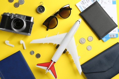 Photo of Flat lay composition with toy airplane and travel items on yellow background