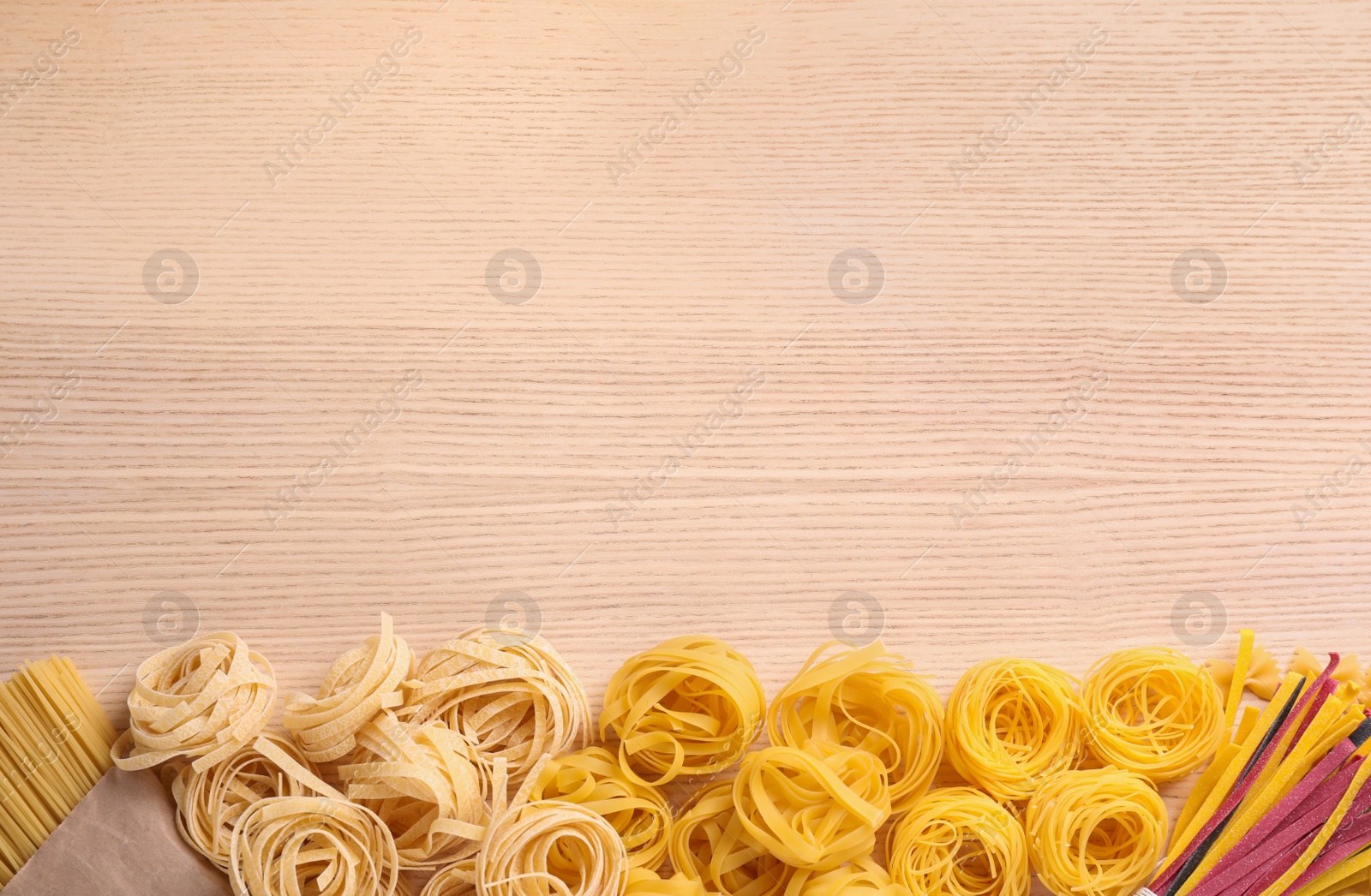 Photo of Different types of pasta on wooden table, flat lay. Space for text