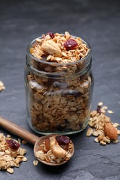 Jar of tasty granola with nuts and dry fruits on black table