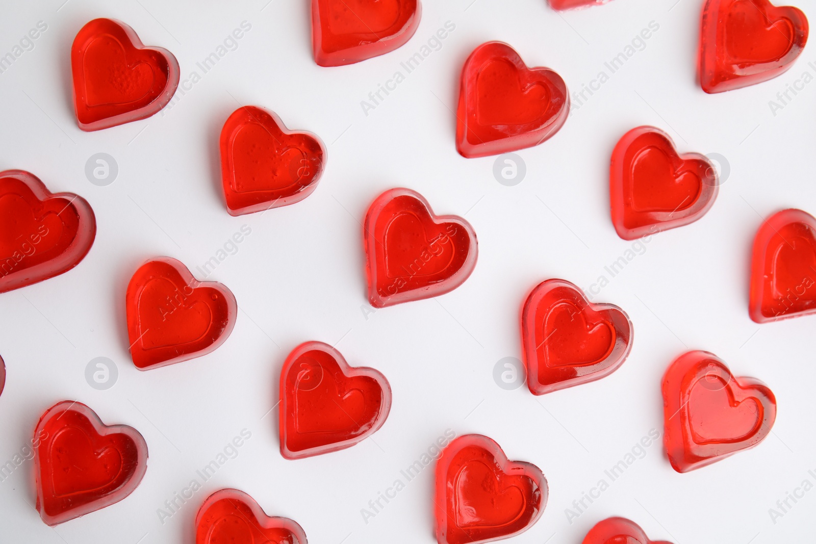 Photo of Sweet heart shaped jelly candies on white background, flat lay