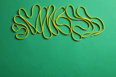 Photo of Yellow shoelaces on green background, flat lay. Space for text