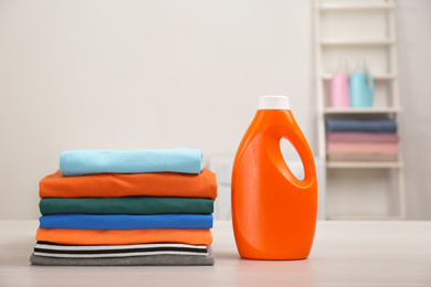 Stack of fresh laundry and detergent on white table in bathroom