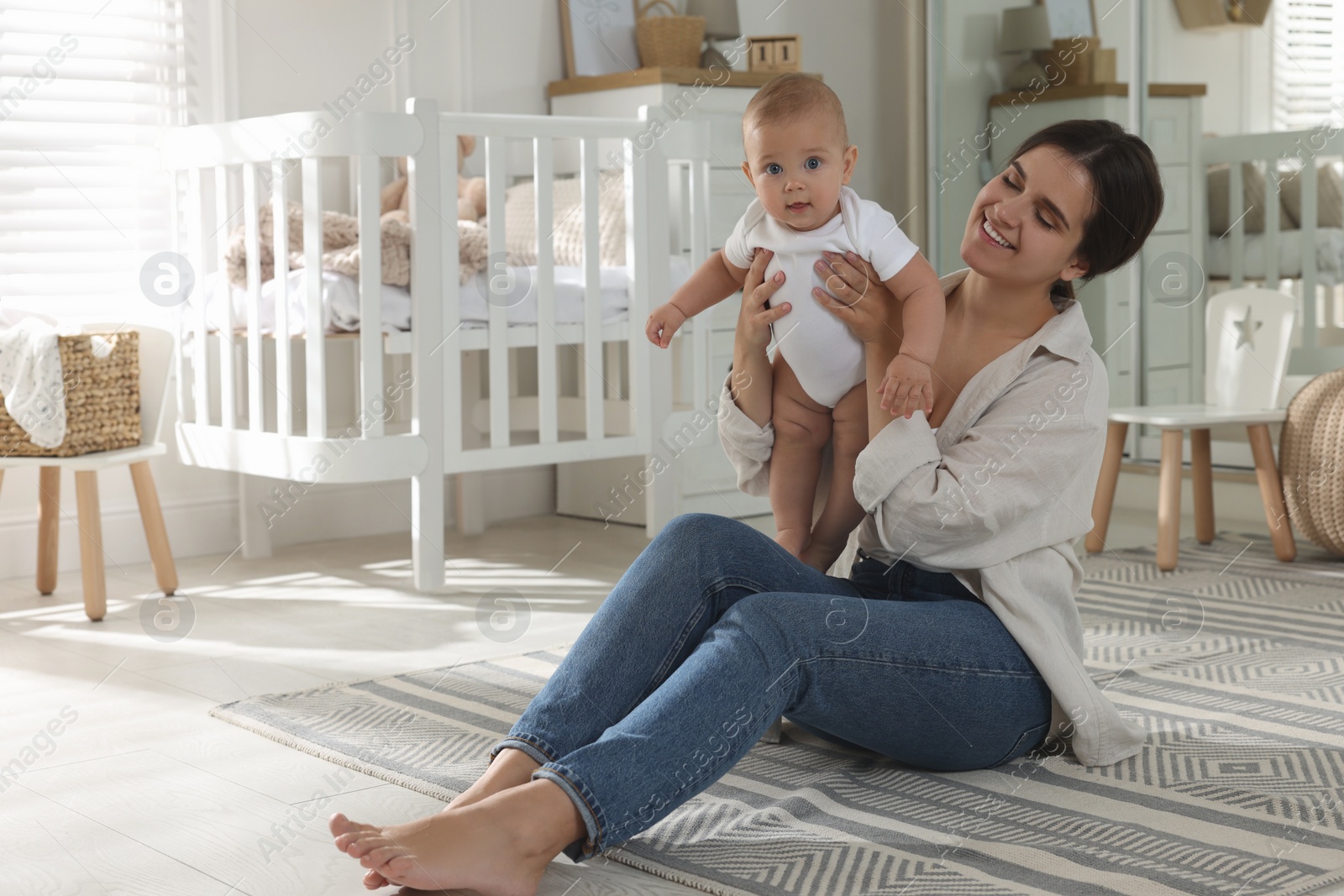 Photo of Happy young mother with her baby in nursery. Space for text