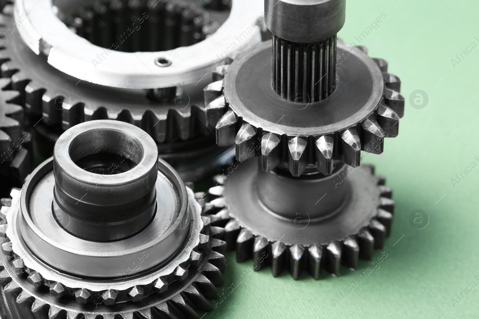 Photo of Different stainless steel gears on light green background, closeup