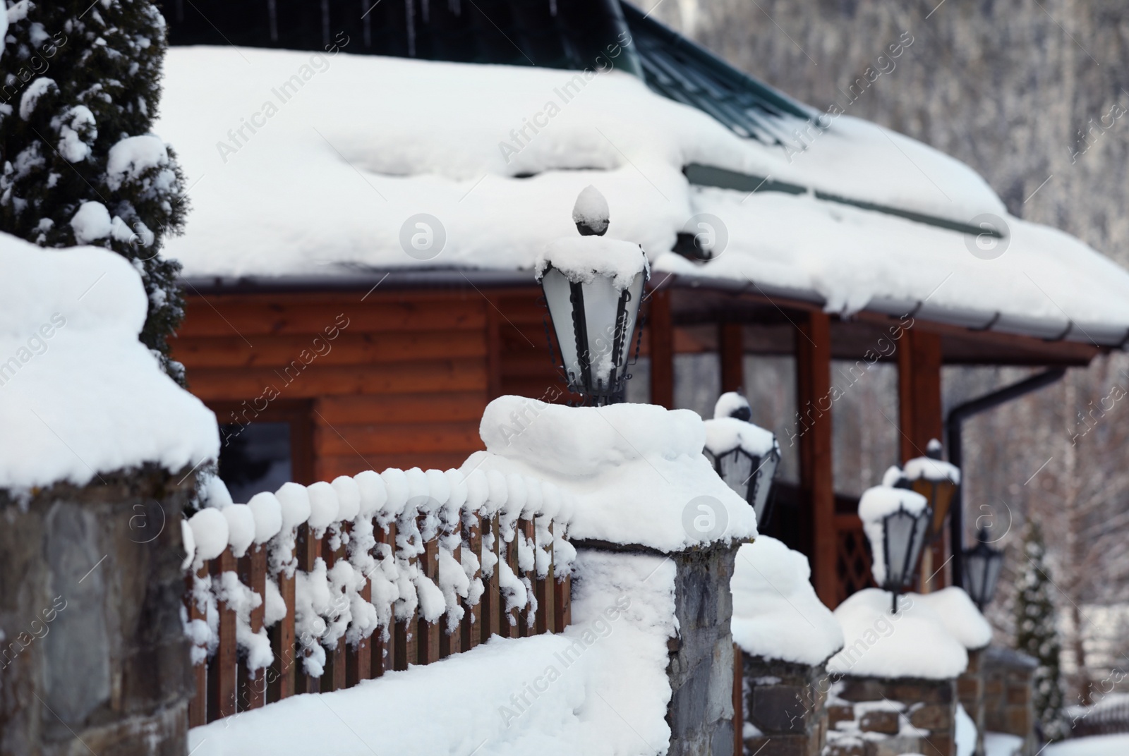 Photo of Fence near cottage covered with snow outdoors on winter day