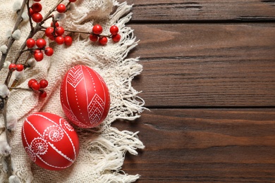 Flat lay composition with painted red Easter eggs on wooden table, space for text