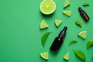 Flat lay composition with lime essential oil on green background. Space for text