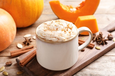 Photo of Cup with tasty pumpkin spice latte on wooden table