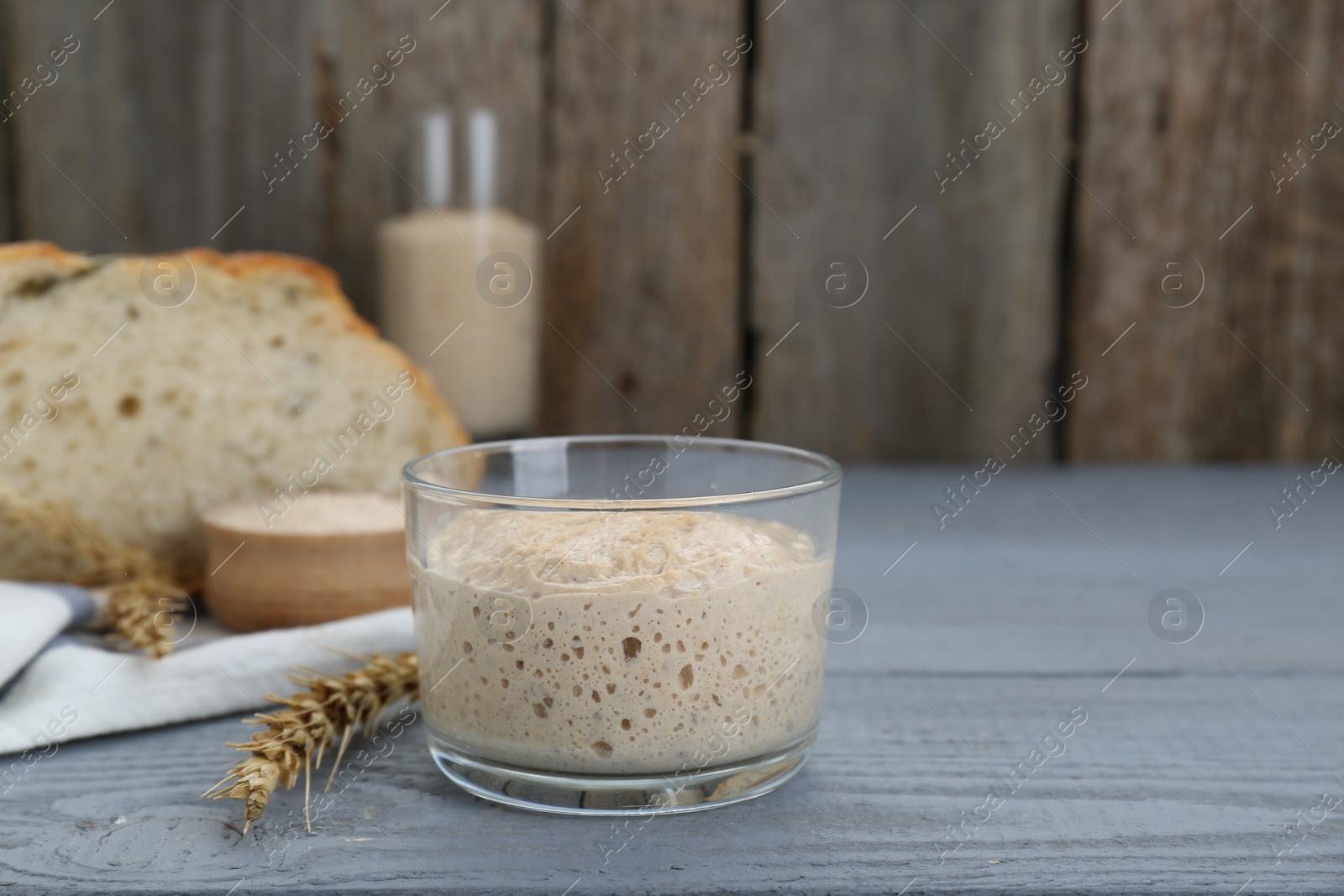 Photo of Glass jar with sourdough on grey wooden table. Space for text
