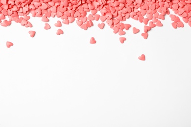Photo of Pink heart shaped sprinkles on white background, view from above. Space for text