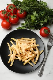 Photo of Delicious French fries with cheese sauce, tomatoes, dill and parsley on white marble table, flat lay