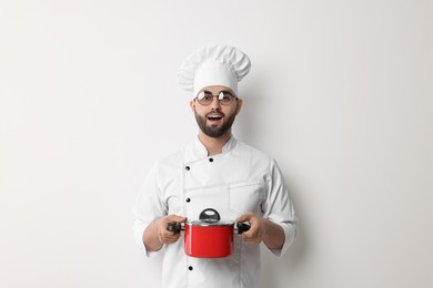 Photo of Professional chef with cooking pot on white background