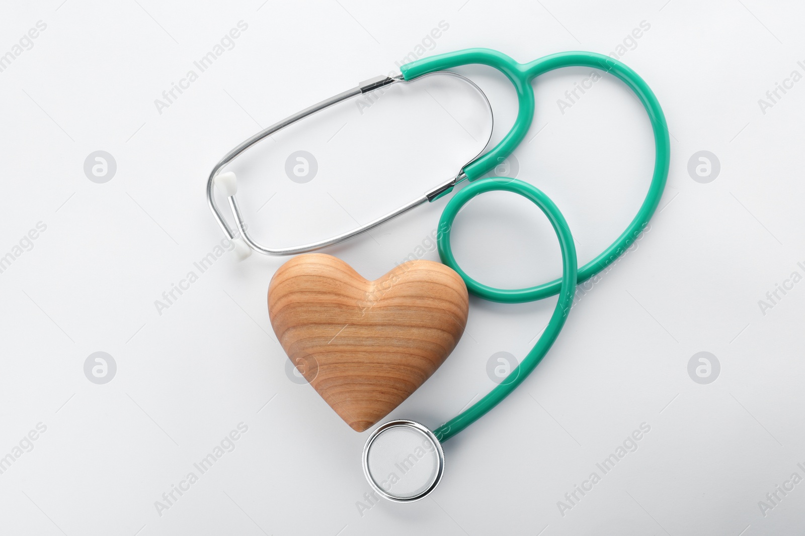 Photo of Stethoscope with wooden heart on white background, top view