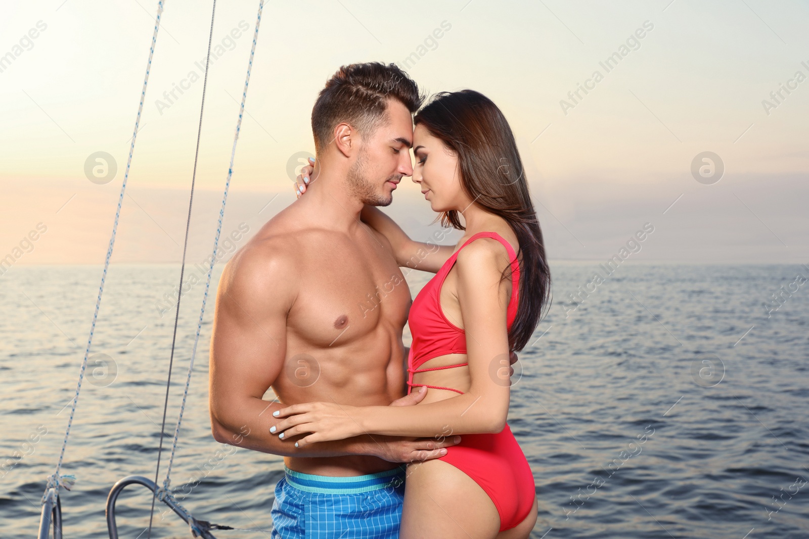 Photo of Young man and his beautiful girlfriend in bikini on yacht. Happy couple during sea trip