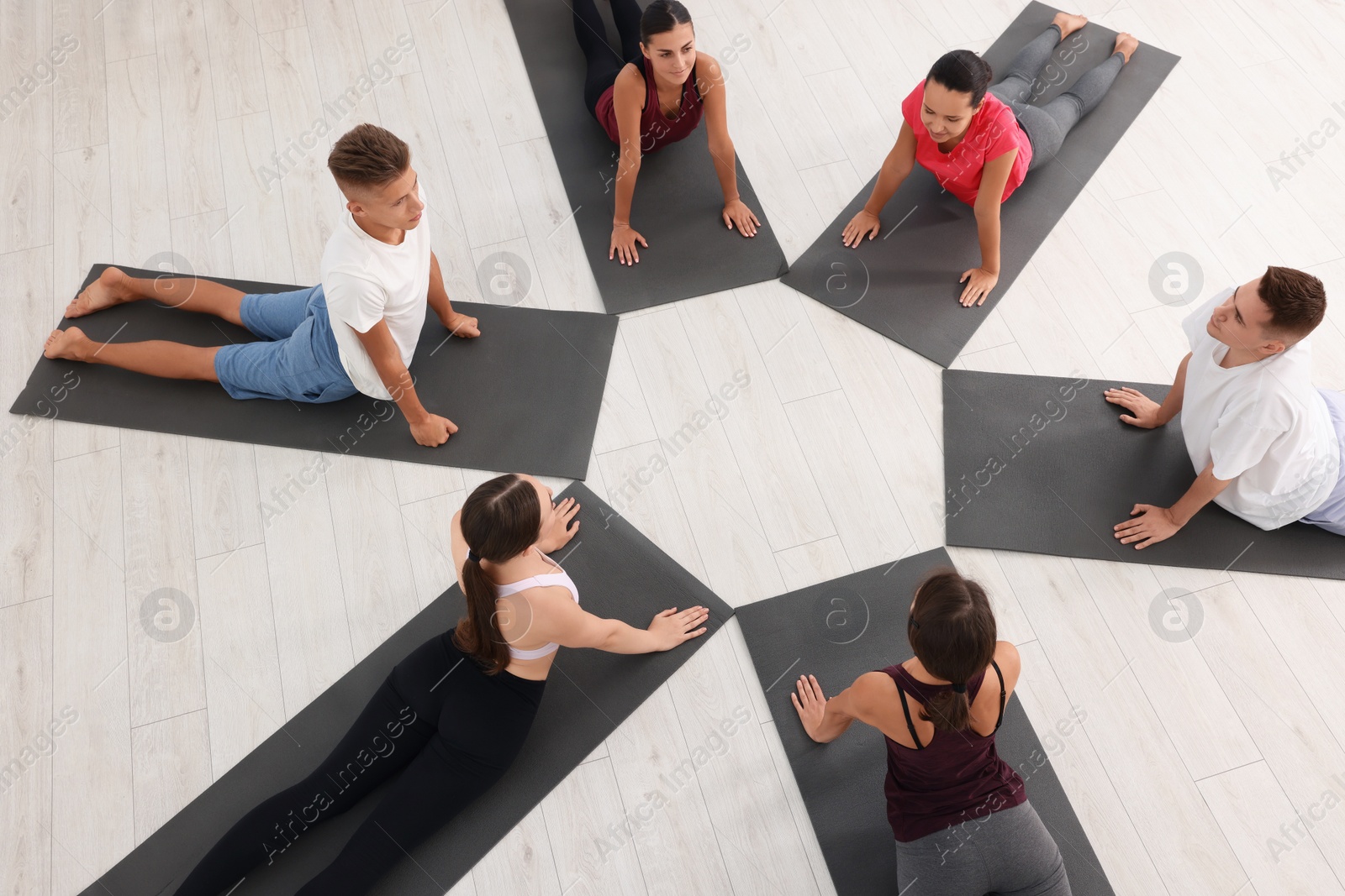 Photo of Group of people practicing yoga on mats indoors, above view