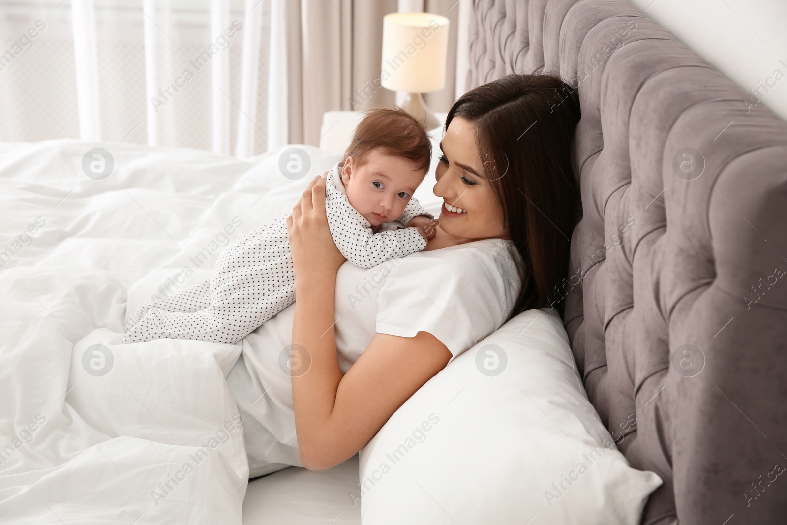 Photo of Happy woman with her cute baby on bed