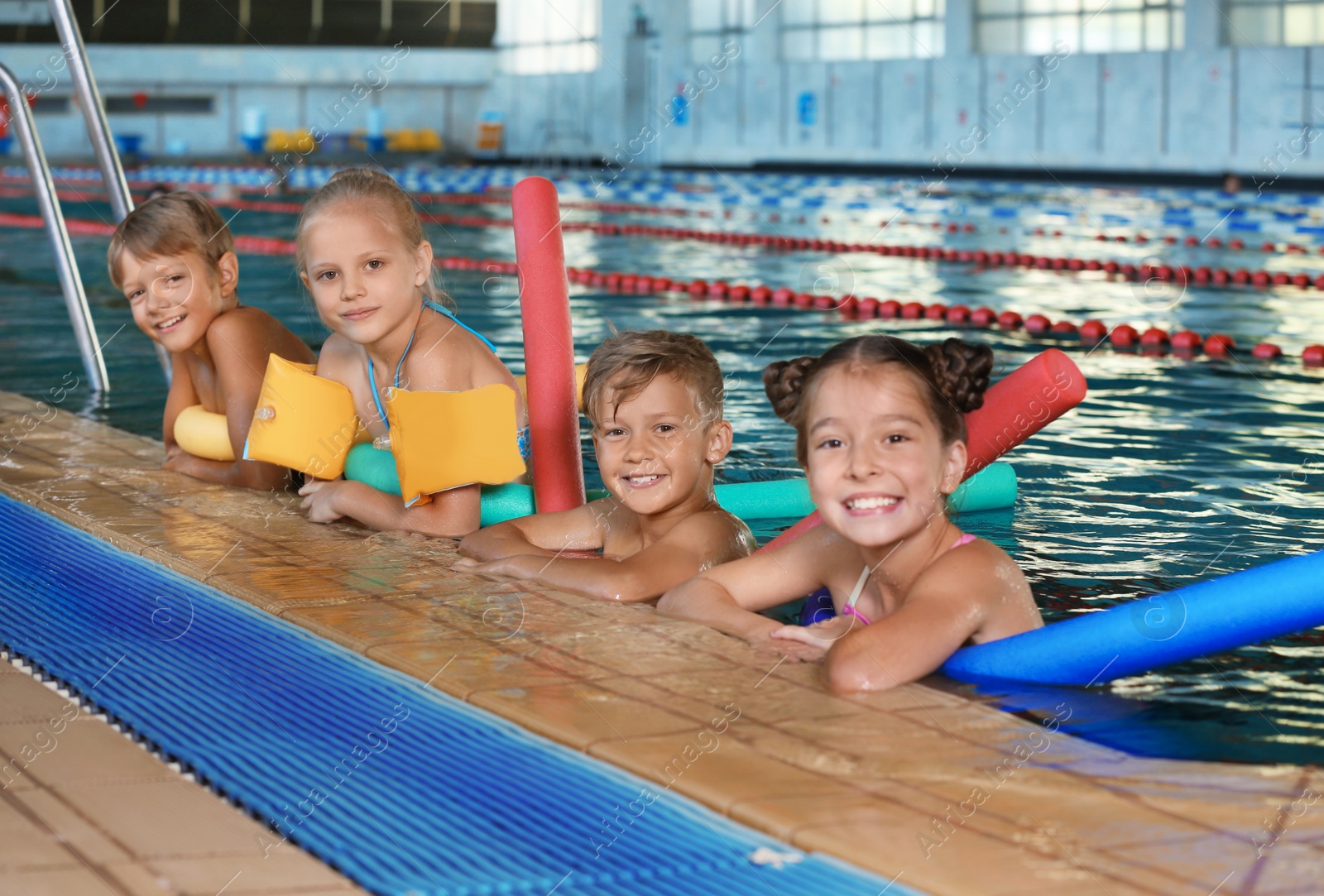 Photo of Little kids with swimming noodles in indoor pool