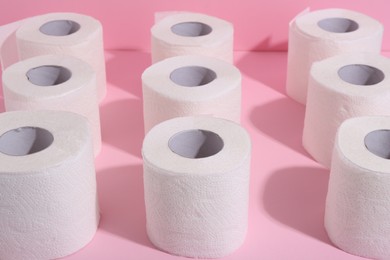 Photo of Many soft toilet paper rolls on pink background, closeup