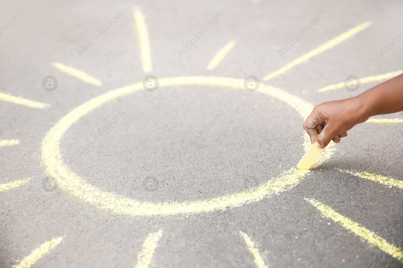 Photo of Little child drawing sun with chalk on asphalt