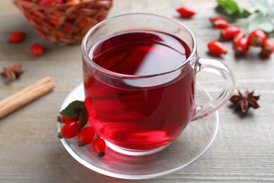 Photo of Aromatic rose hip tea and fresh berries on wooden table, closeup