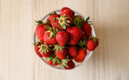 Photo of Glass bowl with ripe strawberries on white wooden table, top view