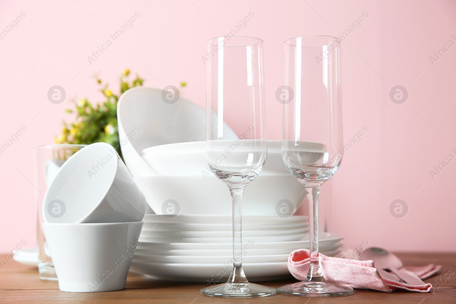 Photo of Set of clean dishes and glasses on table against color background