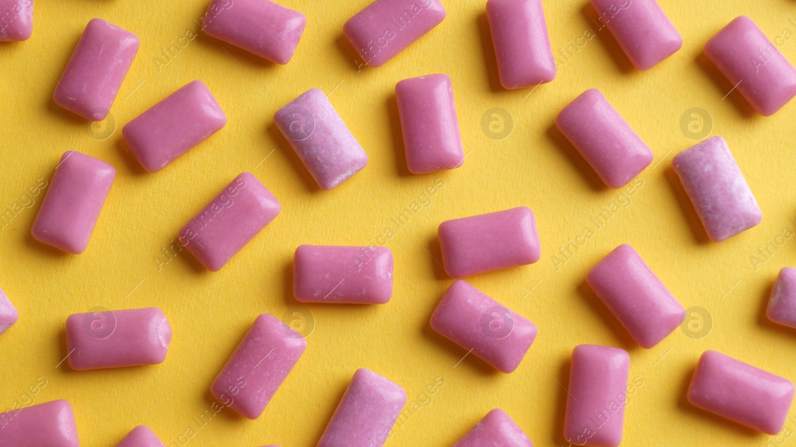 Photo of Sweet chewing gums on yellow background, flat lay