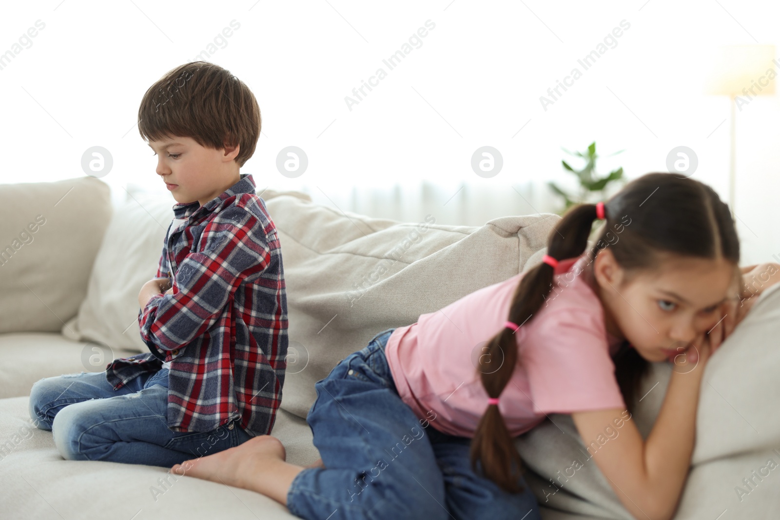 Photo of Upset brother and sister on sofa at home