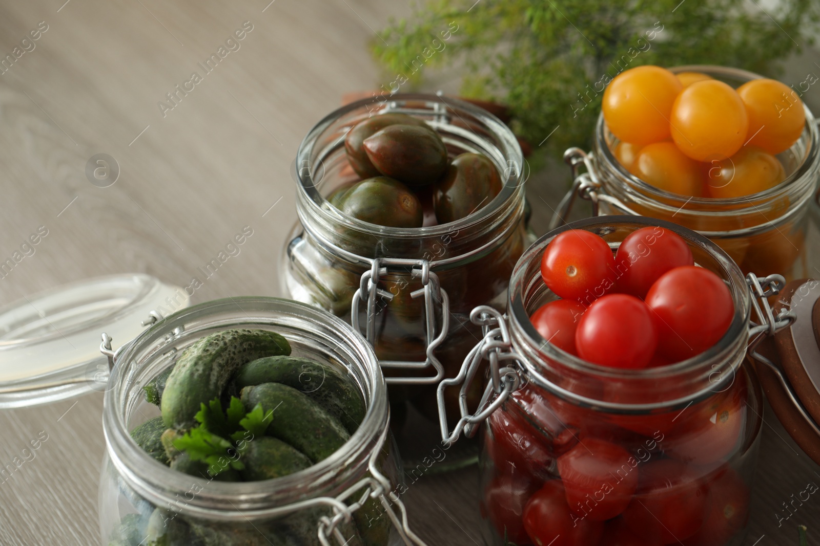 Photo of Pickling jars with fresh vegetables on wooden table, closeup