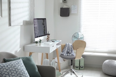 Photo of Comfortable office chair near desk with modern computer indoors