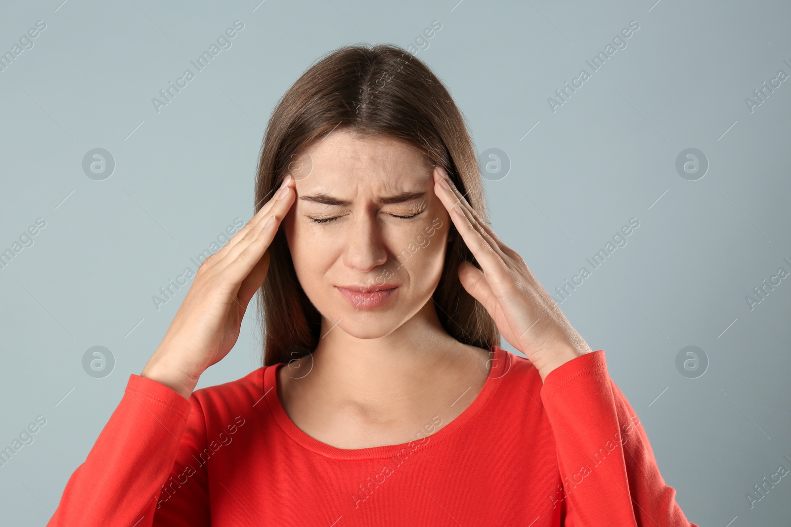 Photo of Young woman suffering from migraine on grey background