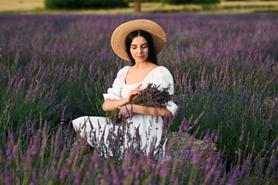 Beautiful young woman with bouquet sitting in lavender field