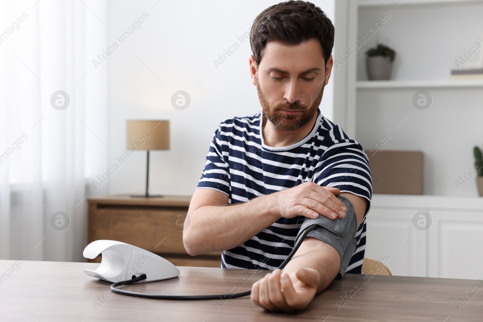 Photo of Man measuring blood pressure in room, space for text