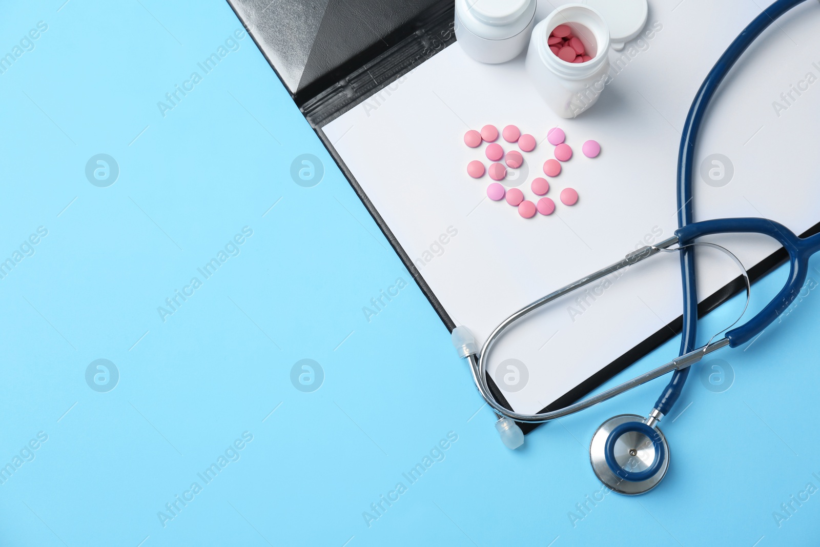 Photo of Stethoscope, clipboard and pills on color background, top view. Medical equipment