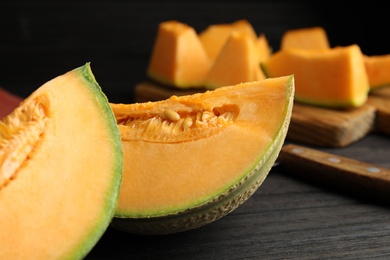 Photo of Tasty fresh cut melon on black wooden table, closeup