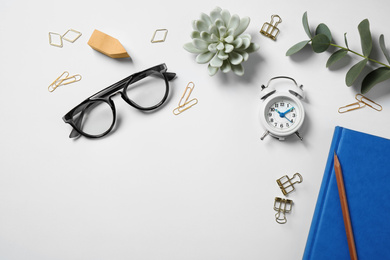 Glasses, alarm clock, eucalyptus and different stationery on white background, top view. Classic blue - color of the Year 2020