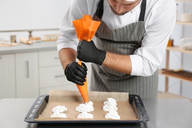 Pastry chef preparing meringues at table in kitchen